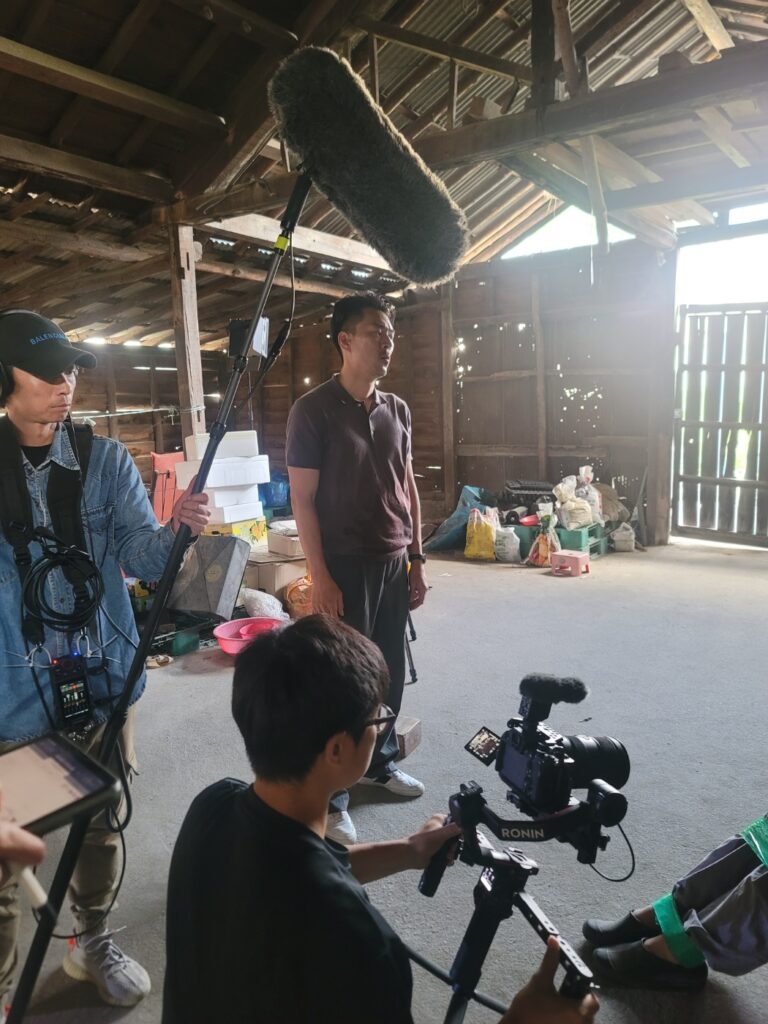 창고 세트에서 붐 마이크와 카메라로 촬영하는 현장